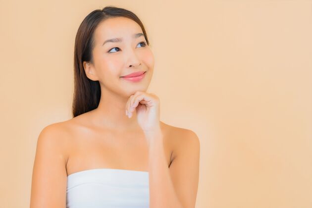 快乐肖像美丽的年轻亚洲女子在温泉与自然化妆米色干净水疗肖像