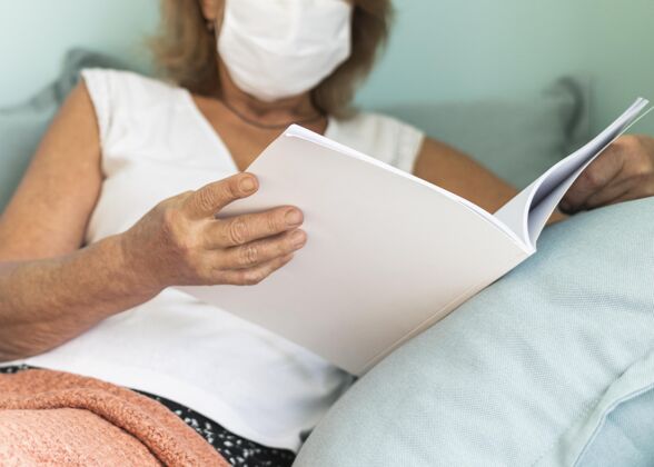 流行病熟女带着医用口罩在大流行期间在家看书水平预防防护