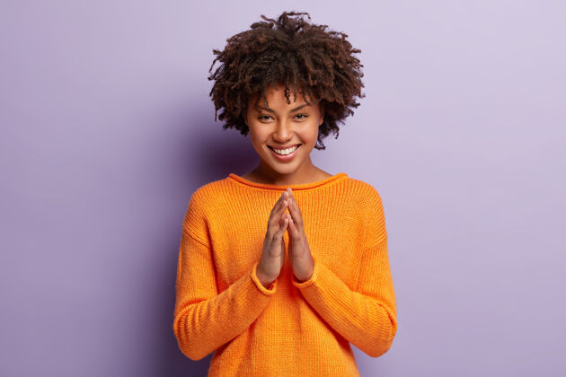 牙齿乐观的黑皮肤女人的照片 非洲式发型 双手合十 笑容灿烂 心满意足人类询问祈祷
