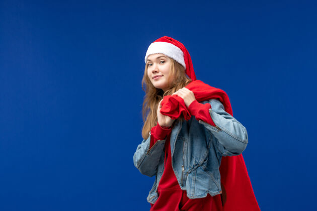 女性正面图：年轻女性 在蓝色背景下 带着装满礼物的袋子过圣诞节快乐可爱年轻人
