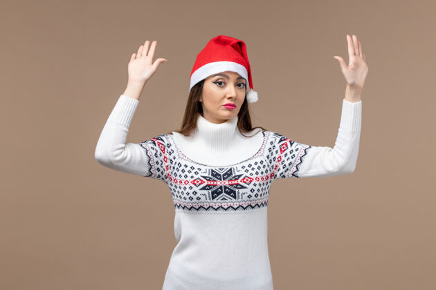 肖像正面图棕色背景上戴着红色圣诞帽的年轻女性圣诞假期感慨开朗年轻情感