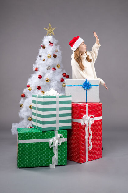 年轻的女性年轻的女性在灰色的礼物购物庆祝圣诞树