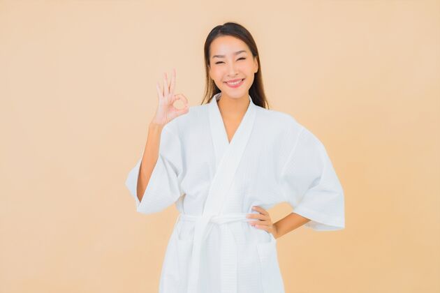 淋浴肖像美丽的亚洲年轻女子穿着米色的微笑浴袍韩国保湿清洁