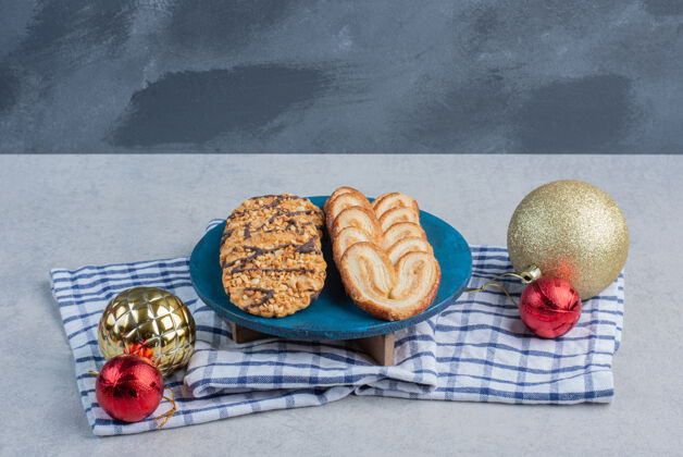 甜点蓝色板上的一捆饼干 旁边是大理石表面毛巾上的圣诞饰品糖糖果甜点