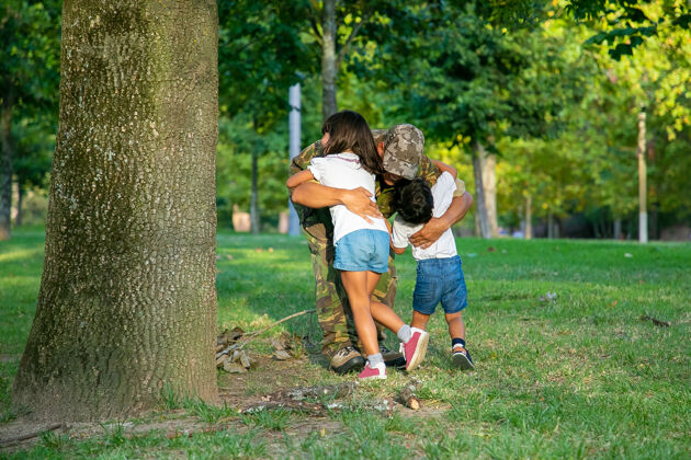 力量爸爸在执行完军事任务后和两个孩子见面 在公园的草地上拥抱孩子们回归黑色父母