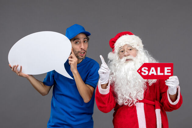 圣诞老人圣诞老人与男信使持有白色标志和灰色墙上的销售横幅前视图男圣诞快乐快乐