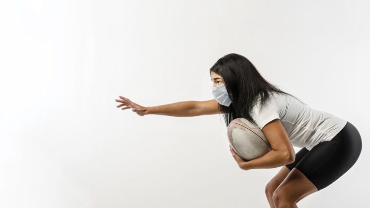 球员带球和医用面罩的女橄榄球运动员侧视图足球橄榄球联盟医疗面具