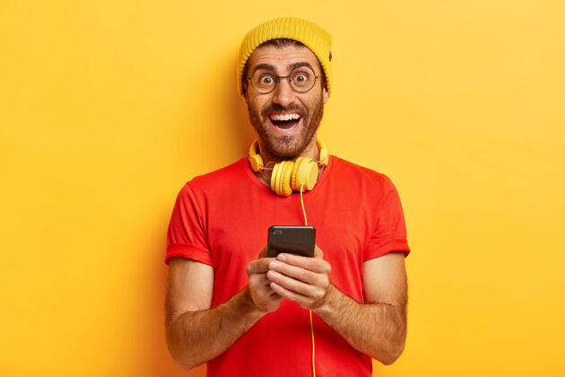 积极乐观的白种人室内照片下载新的手机音乐应用 对着相机微笑 输入信息音乐兴奋小玩意