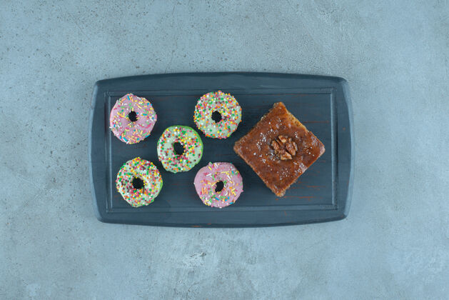 可口一捆油炸圈饼和一块烤面包放在大理石表面的海军蓝板上甜点糖糖果