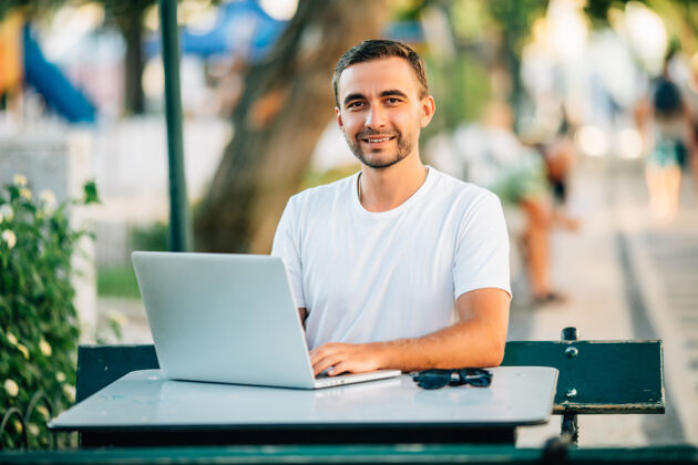 网站年轻帅气的胡须男在街上的咖啡馆里用笔记本电脑互联网社交夏天