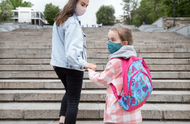 安全回到学校冠状病毒大流行的孩子戴着口罩上学妈妈牵着孩子的手妈妈孩子面具
