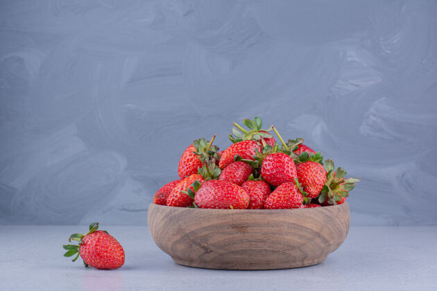 营养一个草莓在大理石背景上的一个木制草莓碗旁边天然碗饮食