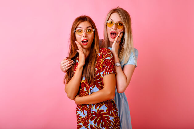 漂亮两个快乐美丽的姐妹最好的朋友时髦的女人在粉红色的工作室背景一起玩头发时尚复制空间