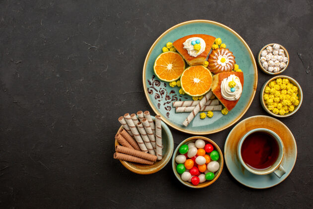 晚餐顶视图美味的派片与新鲜的橘子茶和糖果在黑暗中茶水果饼干
