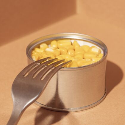 铁用叉子把高角度的玉米脯装在罐头里保存钢容器