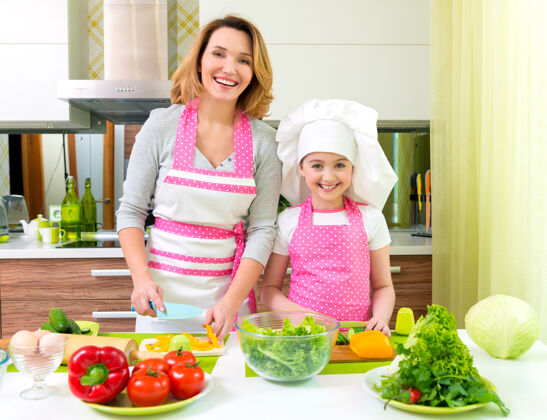 沙拉快乐微笑的母女俩在厨房做沙拉餐切素食