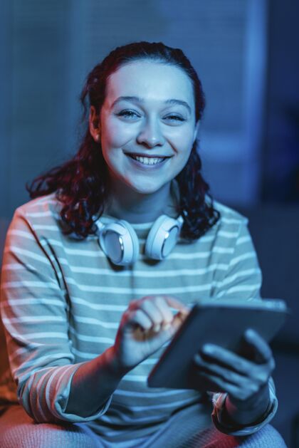 女性在家中使用耳机和平板电脑的笑脸女人的前视图小玩意科技个人