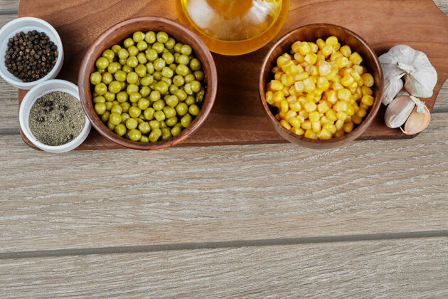 罐装一碗碗煮好的甜玉米和青豆 香料 油和蔬菜放在木板上烹饪有机生的