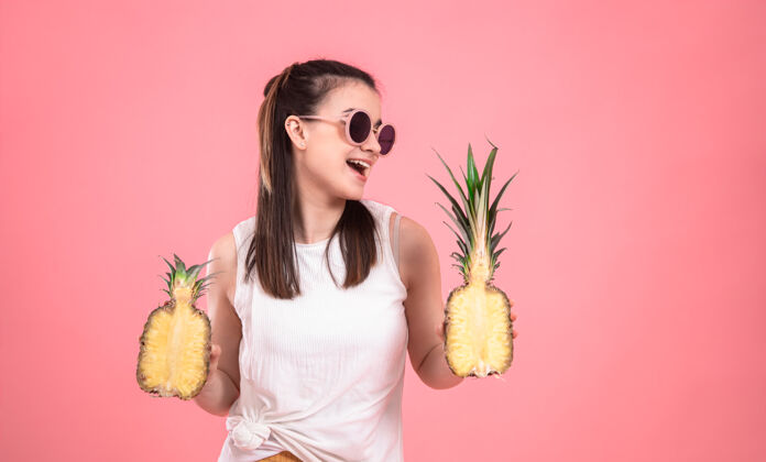菠萝戴着太阳镜的时髦女孩微笑着拿着水果暑假概念模特夏天时尚