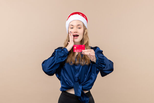 银行正面图年轻女性手持粉色背景的红色银行卡度假照片新年感慨圣诞钱微笑肖像微笑