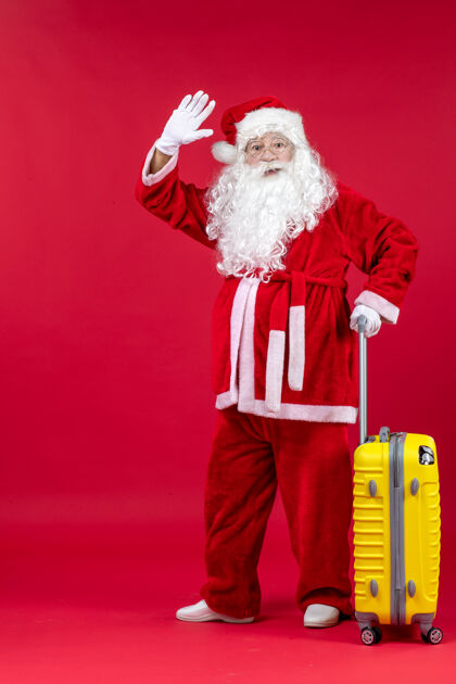 圣诞老人红墙上准备旅行的黄包圣诞老人的正视图旅行包快乐