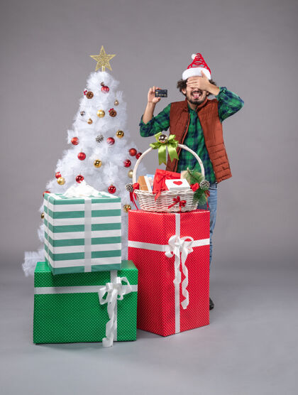 礼物年轻的男性在灰色的圣诞礼物周围周围灰色圣诞老人