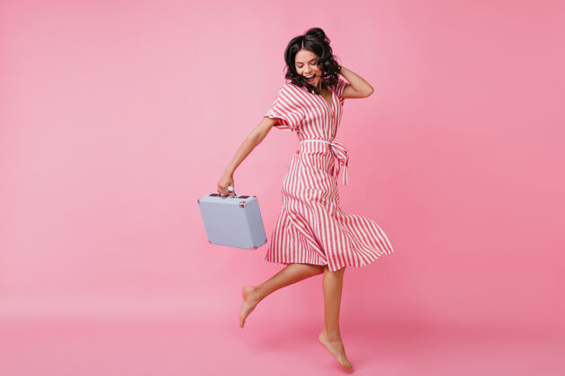 粉色意气风发的苗条女孩手里拿着包 一边玩乐一边跳舞身着裹身裙的意大利模特照可爱派对优雅