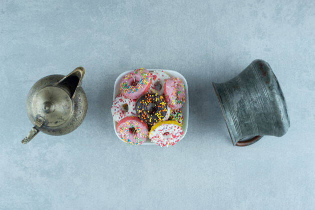 烘焙在一个茶壶和一个大理石罐子之间放着一小盘甜甜圈美味视图糖