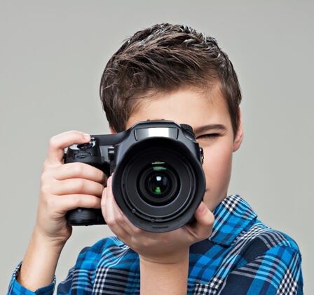 男孩男孩用单反相机拍照十几岁的男孩拿着相机拍照单反青少年镜头