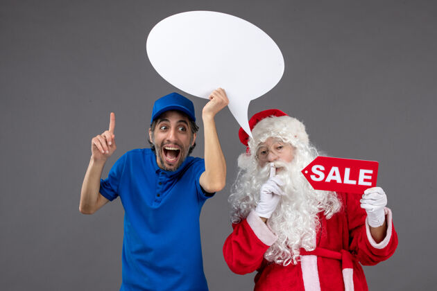 举行圣诞老人与男信使手持白色标志和灰色墙上的销售横幅的正面视图十二月销售男人