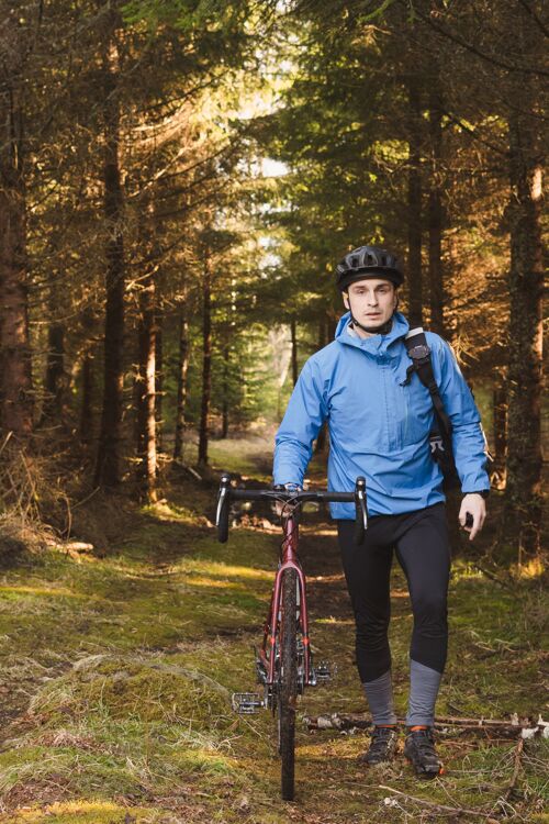 自行车骑自行车的人穿着蓝色外套 戴着头盔在高大的公园里森林道路户外