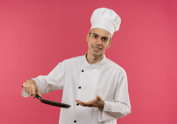 拿面带微笑的年轻男厨师身穿厨师制服 手持一只带复印空间的煎锅穿分厨师