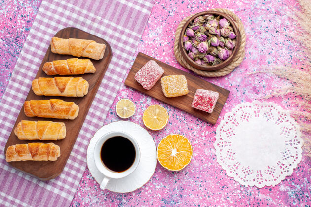 茶俯瞰美味的百吉饼 配上一杯茶和果酱 背景为浅粉色蛋糕淡粉色食物