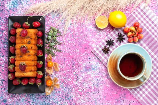 美味在粉红色的桌子上放着美味的蛋糕 红色的新鲜草莓茶和柠檬食物面团糖