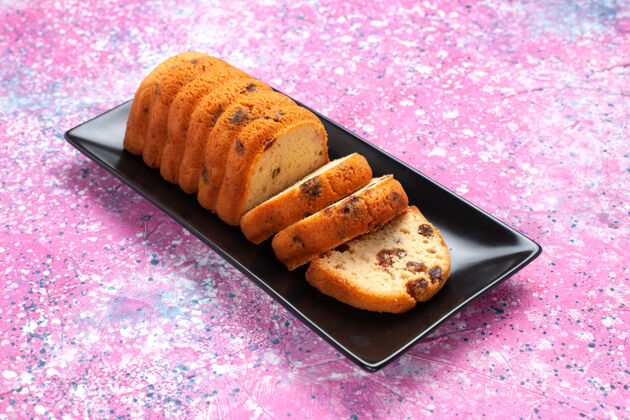 派在粉红色的桌子上切的美味蛋糕切片棕色饼干