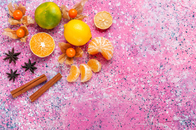 柑橘顶视图新鲜酸橘子与柠檬和肉桂的粉红色背景橘子水果苹果