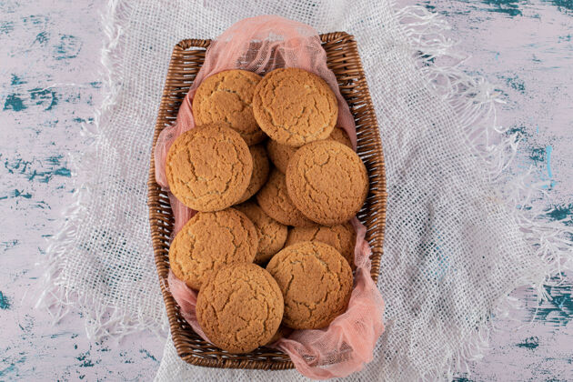 奶油放在木制篮子里的燕麦片饼干 放在粉红色的厨房毛巾上视图糕点自制
