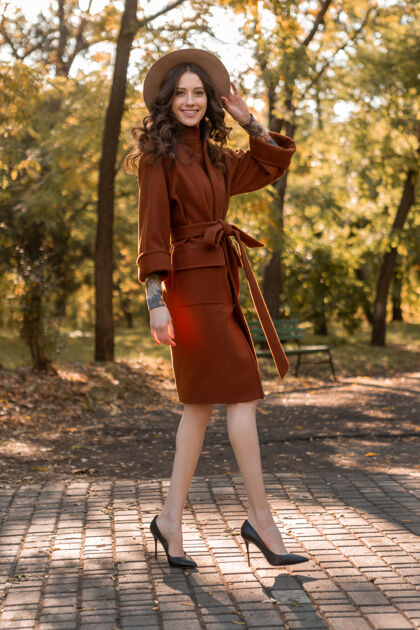 配饰迷人时尚微笑的瘦身女子卷发漫步公园身着暖棕色外套 秋日时尚街头风户外漂亮优雅