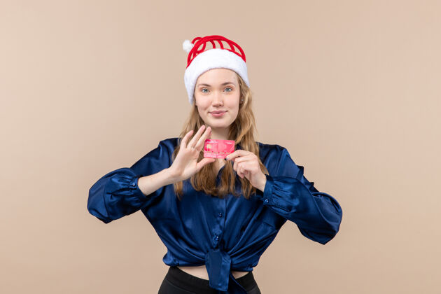 年轻的女人正面图年轻女性手持红色银行卡放在粉色办公桌上度假圣诞钱合影新年感慨孩子情感女人