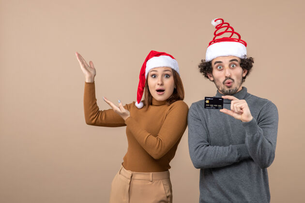 红色圣诞节心情激动满意惊喜酷酷情侣戴红色圣诞老人帽出示银行卡女人展示帽子