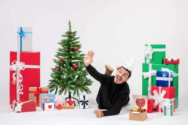 礼物年轻人躺在白色墙上的节日礼物周围的正面视图新郎前面圣诞节