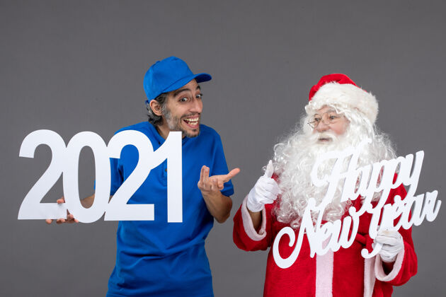 圣诞老人圣诞老人与男信使举行和新年快乐和2021年板灰墙的正面视图帽子节日人们
