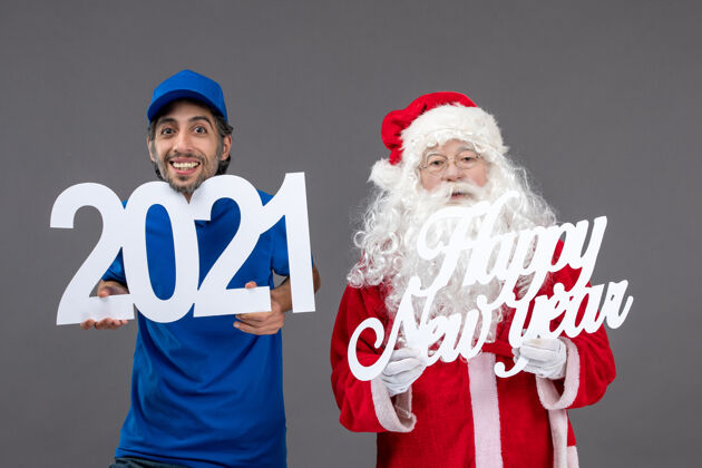 快乐圣诞老人与男信使举行和新年快乐和2021年板灰墙的正面视图圣诞老人人前面