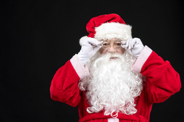 圣诞老人圣诞老人穿着经典的红色套装 留着白胡子 站在黑色的墙上前面站立男人