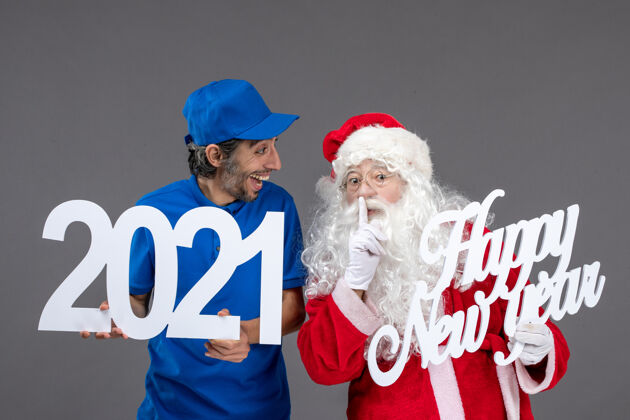庆祝圣诞老人与男信使举行和新年快乐和2021年板灰墙的正面视图节日圣诞老人快乐