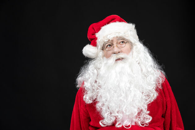 节日圣诞老人穿着经典的红色套装 黑墙上留着白胡子的正面图圣诞快乐西装