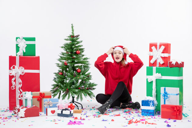 情感年轻女子围坐在白墙上的礼物面前节日快乐圣诞树
