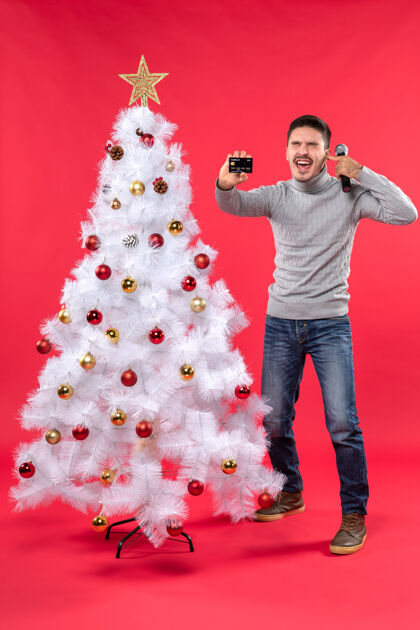 电话圣诞气氛 骄傲的家伙站在装饰好的圣诞树旁 拿着麦克风和电话 合上耳朵骄傲圣诞树结束