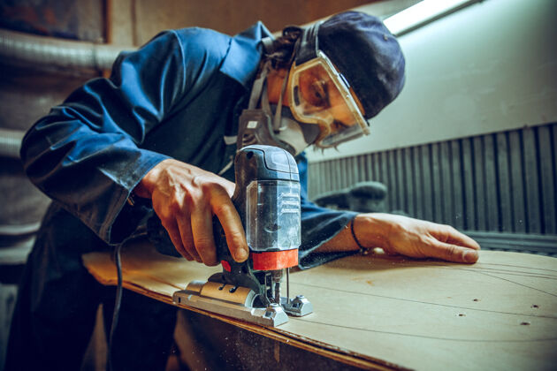 锯使用圆锯切割木板的木匠男工人或手持电动工具的手巧工人的施工详图设备手工木工