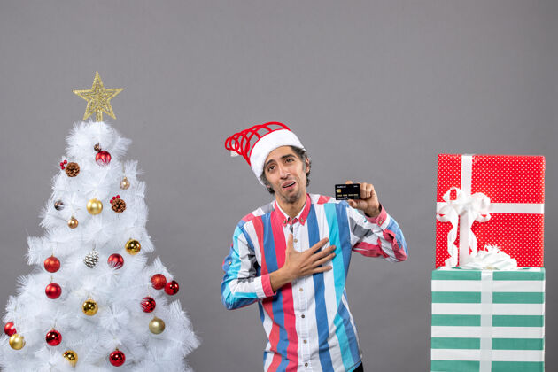 树正面图幸福的男人把手放在胸前站在白色圣诞树旁圣诞人胸